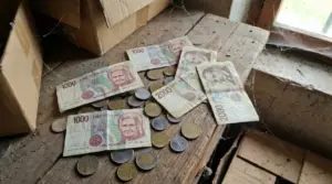 Vecchie banconote e monete in lire italiane su un tavolo polveroso in soffitta, accanto a scatole di cartone